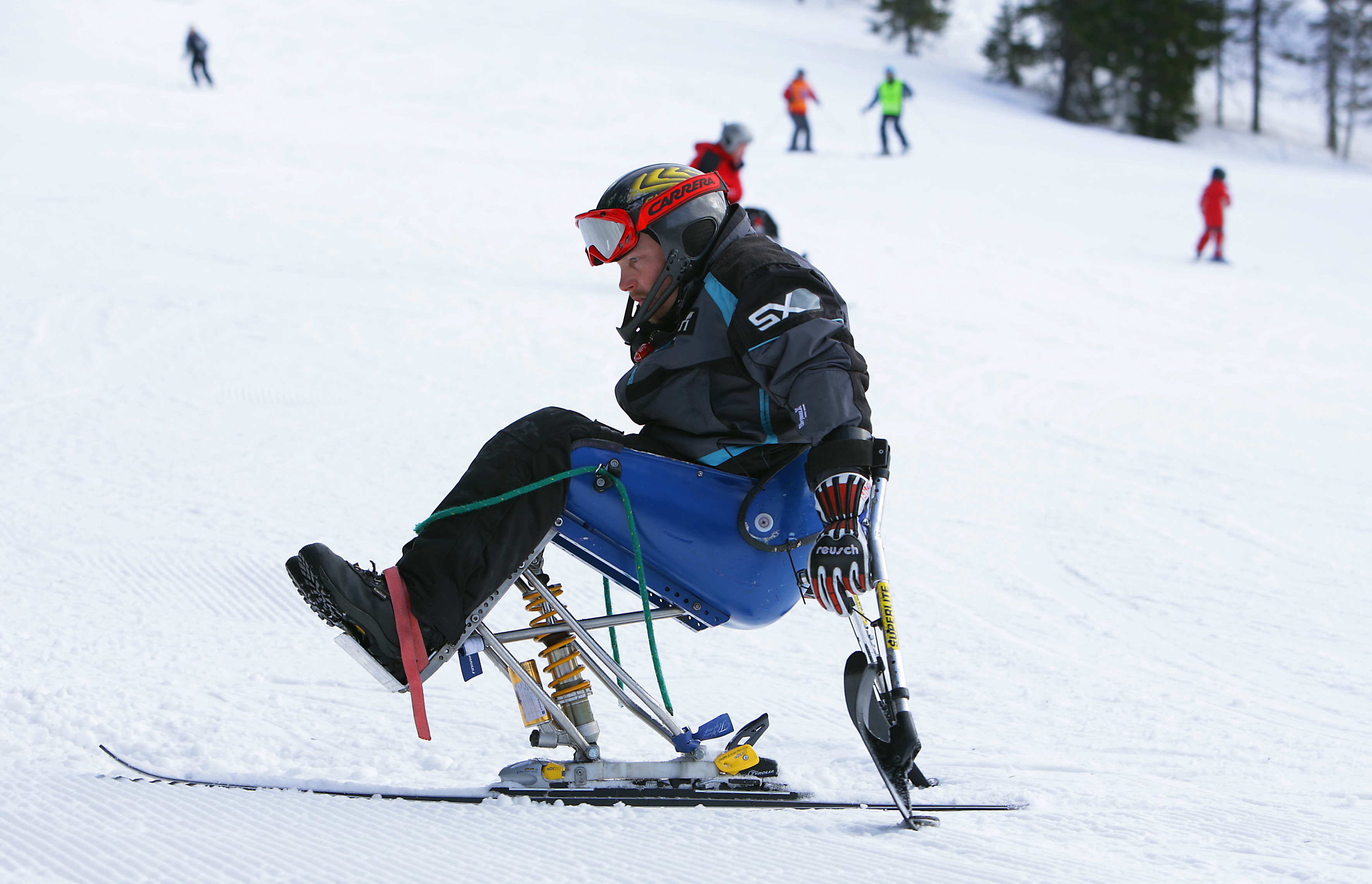 Kuvassa henkilö istuu laskettelukelkassa rinteessä.
